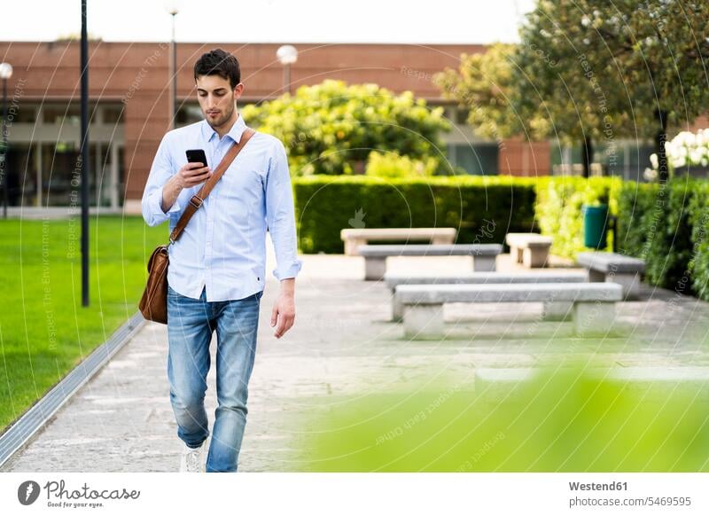 Young man using smartphone in the city shirts benches telecommunication phones telephone telephones cell phone cell phones Cellphone mobile mobile phones