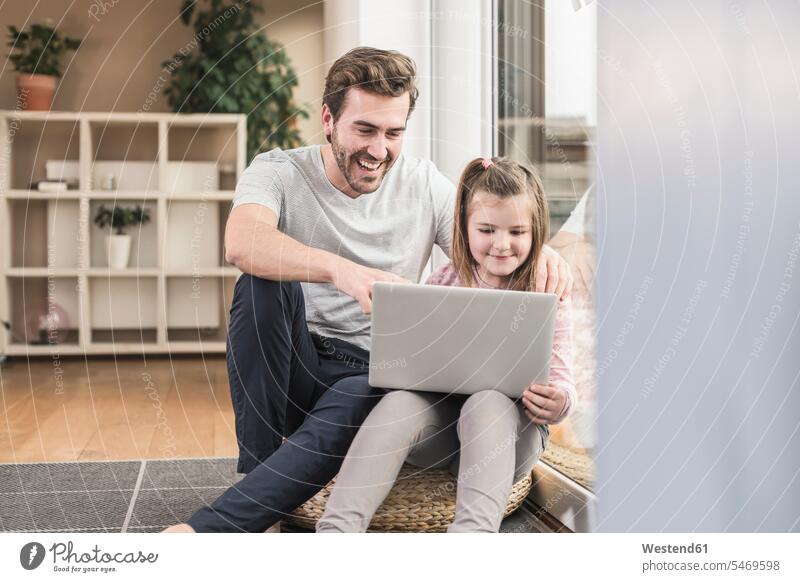 Young man and little girl surfing the net together Germany sitting on ground Sitting On The Floor Sitting On Floor using laptop using a laptop Using Laptops