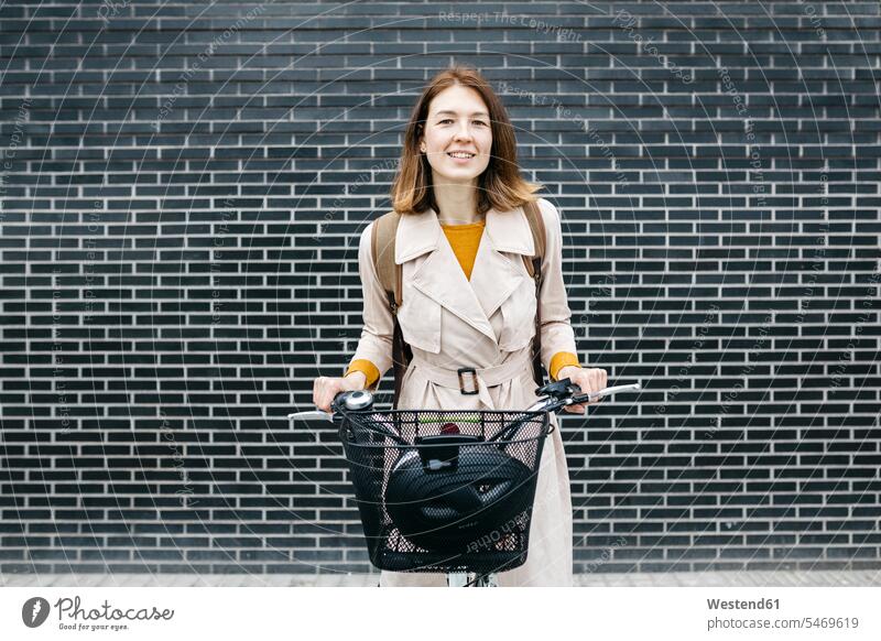 Portrait of smiling woman with e-bike at a brick wall portrait portraits bicycle bikes bicycles smile brick walls E-Bike Electric bicycle Electric Bike females