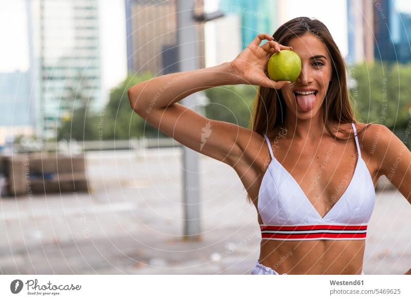 Portrait of attractive sportive young woman holding an apple sticking out tongue females women Apple Apples Sportswear Activewear Sport Clothes Sports Clothes
