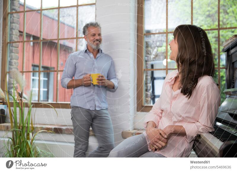 Mature couple at home taking a break, talking and drinking coffee Coffee Taking a Break resting twosomes partnership couples speaking Drink beverages Drinks
