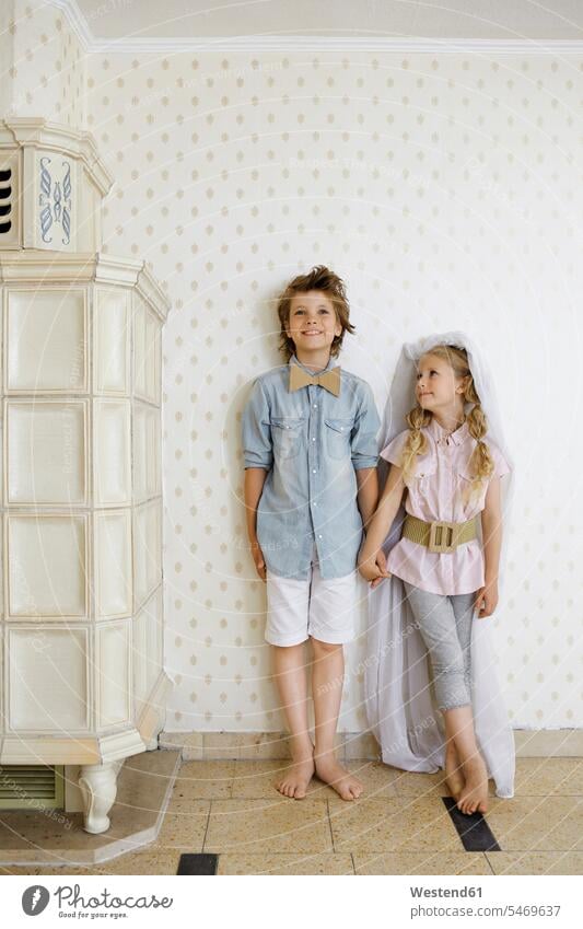 Dressedup boy and girl standing hand in hand at a wall bow - accessory bows Bow Ties bow-tie bowtie wall paper wall papers wallpapers smile play Retro