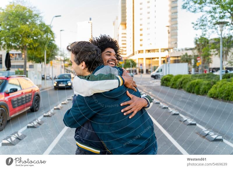 Two happy friends embracing in the city, Barcelona, Spain mate coat coats jackets greet smile embrace Embracement hug hugging delight enjoyment Pleasant