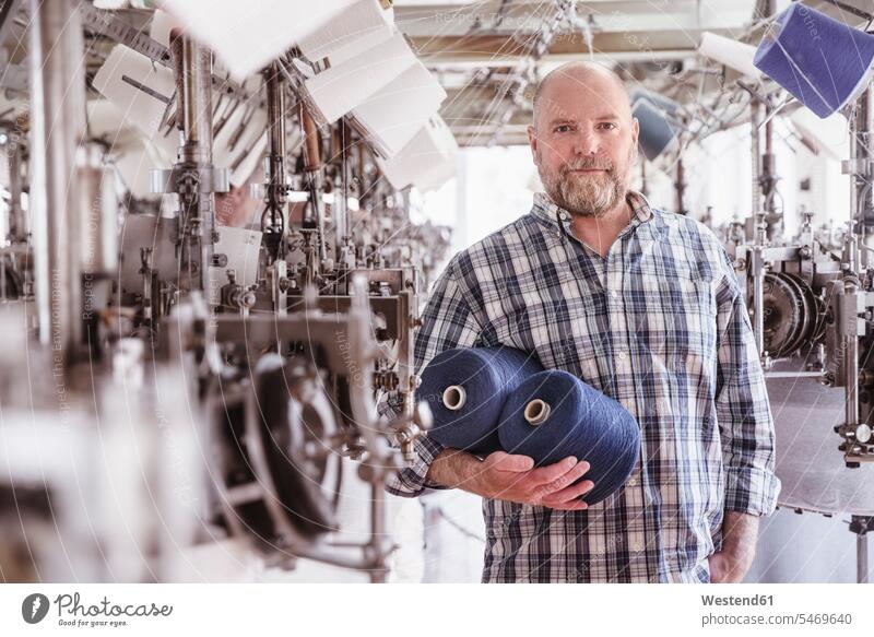 Portrait of man holding cotton reels in a textile factory human human being human beings humans person persons caucasian appearance caucasian ethnicity european