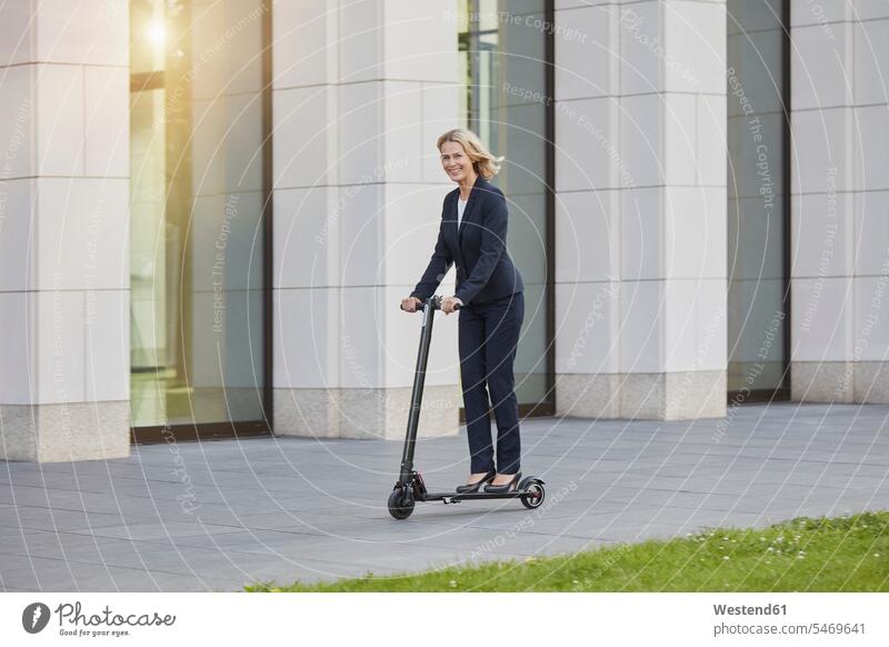 Businesswoman on e-scooter passing office building in the city Occupation Work job jobs profession professional occupation business life business world