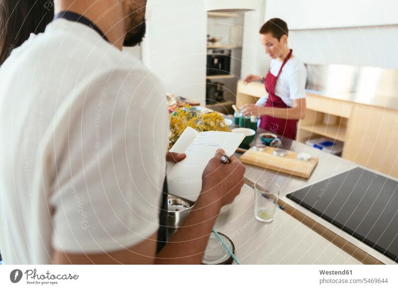 Close-up of man taking notes in a cooking workshop cooking class kitchen training course Exercise Class Training Class making a note note taking Part Of