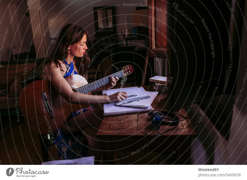 Young woman practicing guitar at home color image colour image domestic life domestic scene indoors indoor shot indoor shots interior interior view Interiors
