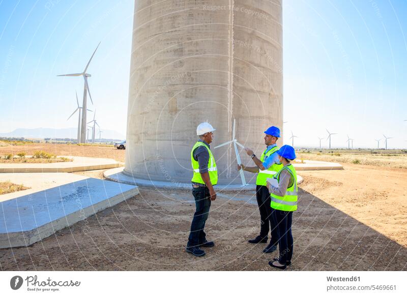 Three engineers with wind turbine model discussing on a wind farm wind park discussion models wind turbines wind power plant wind energy renewable energy
