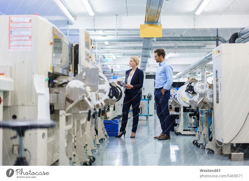 Male technician standing near businesswoman analyzing machinery at factory color image colour image indoors indoor shot indoor shots interior interior view