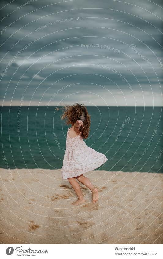 Carefree girl dancing on sand against sea color image colour image outdoors location shots outdoor shot outdoor shots dusk evening twilight in the evening