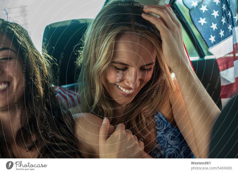 Happy female friends sitting in car during road trip color image colour image attitude Vehicle Interior day daylight shot daylight shots day shots daytime
