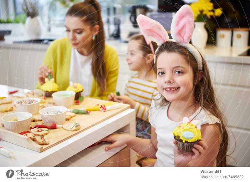 Portrait of smiling girl showing Easter cupcake in kitchen portrait portraits smile cup cake Cup cakes Cupcakes females girls celebration Red-Letter Day