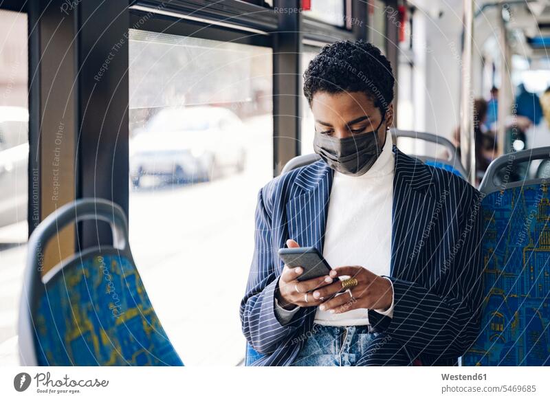 Young businesswoman using mobile phone in bus during COVID-19 color image colour image Vehicle Interior day daylight shot daylight shots day shots daytime