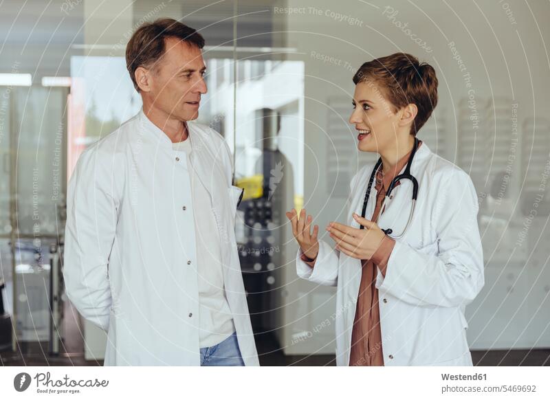 Two confident doctors standing in practice, discussing physicians smiling smile team discussion meeting Female Doctor Female Doctors medical practice
