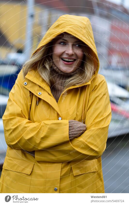 Denmark, Copenhagen, portrait of happy woman at city harbour in rainy weather happiness portraits town cities towns females women outdoors outdoor shots