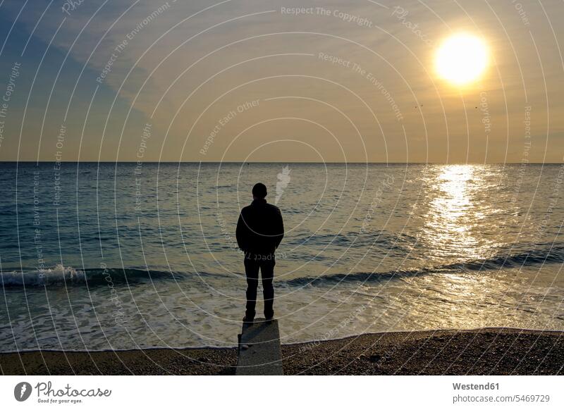 Italy, Liguria, Riviera di Ponente, Noli, man standing at beach at sunrise men males Sea ocean Wanderlust Itchy Feet loneliness lonely solitude alone solitary