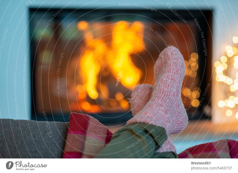 Legs of young woman wearing socks relaxing against fireplace at home color image colour image Germany leisure activity leisure activities free time leisure time