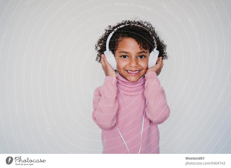 Portrait of smiling little girl wearing pink turtleneck pullover listening music with headphones human human being human beings humans person persons 1