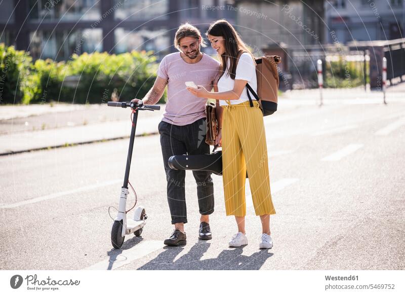 Young couple with electric scooter and smartphone on the street back-pack back-packs backpacks rucksack rucksacks bags T- Shirt t-shirts tee-shirt Instrument