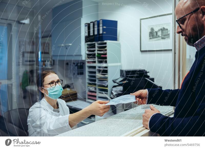 Employee at reception desk of hospital ward handing over mask to visitor health healthcare Healthcare And Medicines medical medicine disease diseases ill