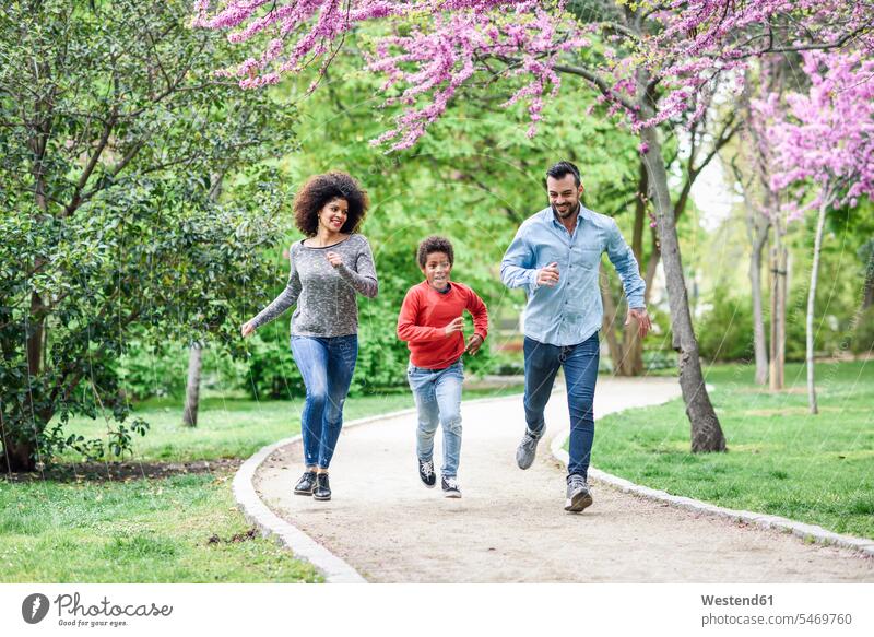 Happy family running and playing in a park Spain boy boys males Quality Time Walkway childhood toothy smile big smile open smile laughing playful togetherness