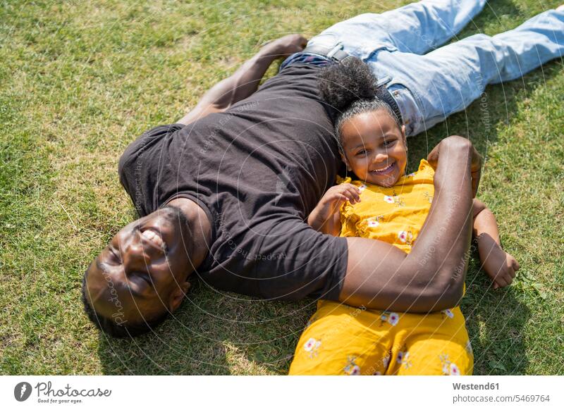 Happy father and daughter lying on a meadow in a park relax relaxing cuddle snuggle snuggling smile seasons summer time summertime summery relaxation delight