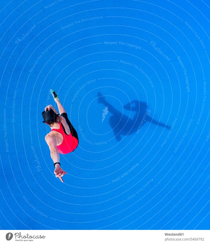 Jumping young woman and her shadow on blue background, top view females women shadows Shades jumping Leaping Adults grown-ups grownups adult people persons