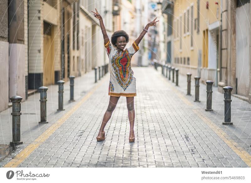 Happy young woman standing with arms outstretched in the middle of a street human human being human beings humans person persons African black black ethnicity