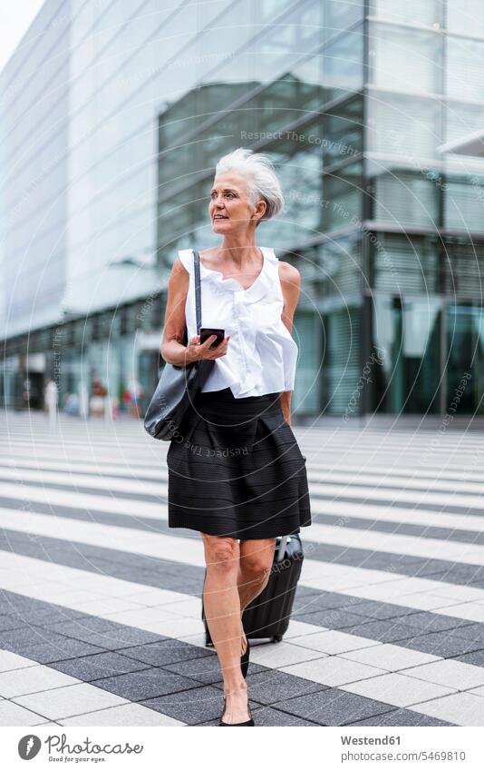 Senior woman with cell phone and baggage on the move females women senior women elder women elder woman old senior woman mobile phone mobiles mobile phones