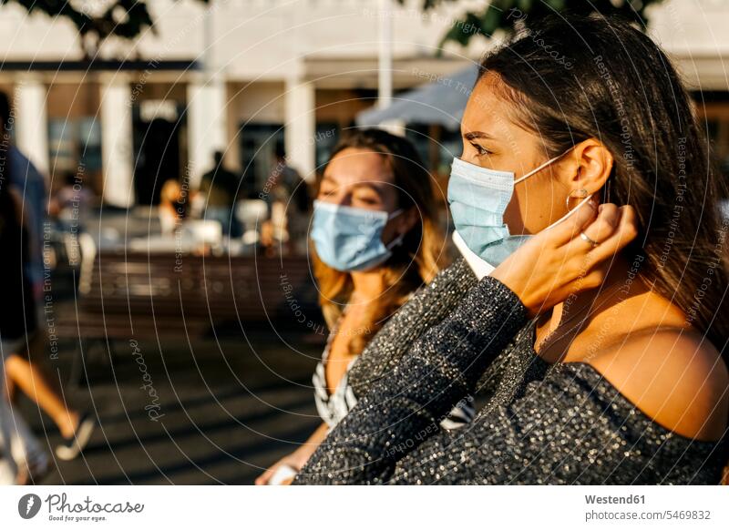 Young friends wearing protective mask in city color image colour image outdoors location shots outdoor shot outdoor shots sunset sunsets sundown atmosphere