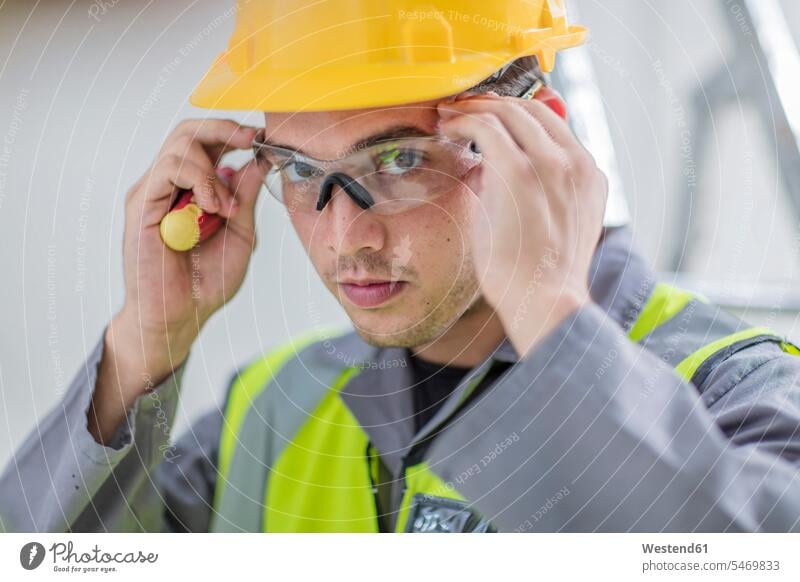 Electrician putting on protective glasses safety glasses Protective Eyeglasses safety goggles Protective Glasses Protective Eyewear Protective Goggles caucasian