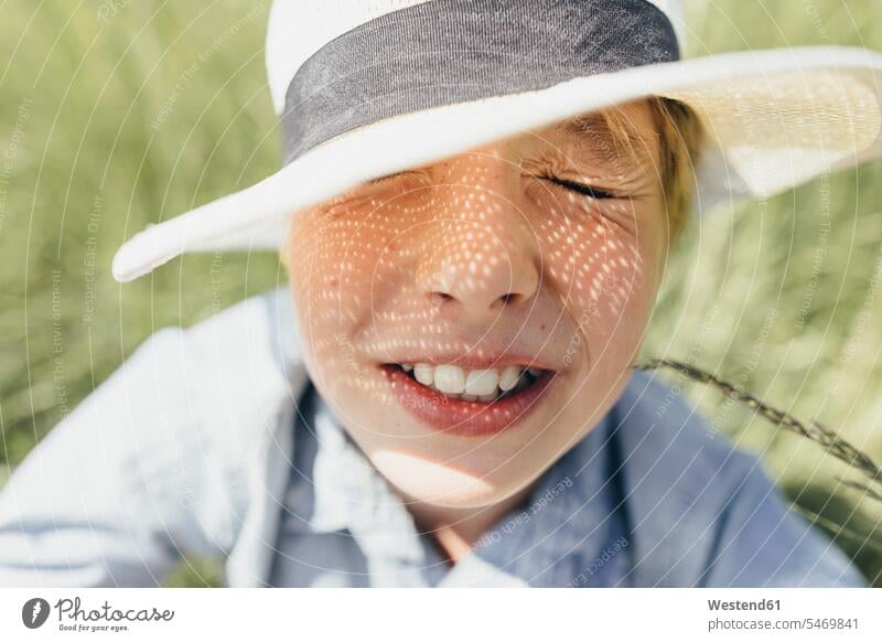 Boy with closed eyes wearing a hat sitting in field Field Fields farmland boy boys males hats Seated child children kid kids people persons human being humans