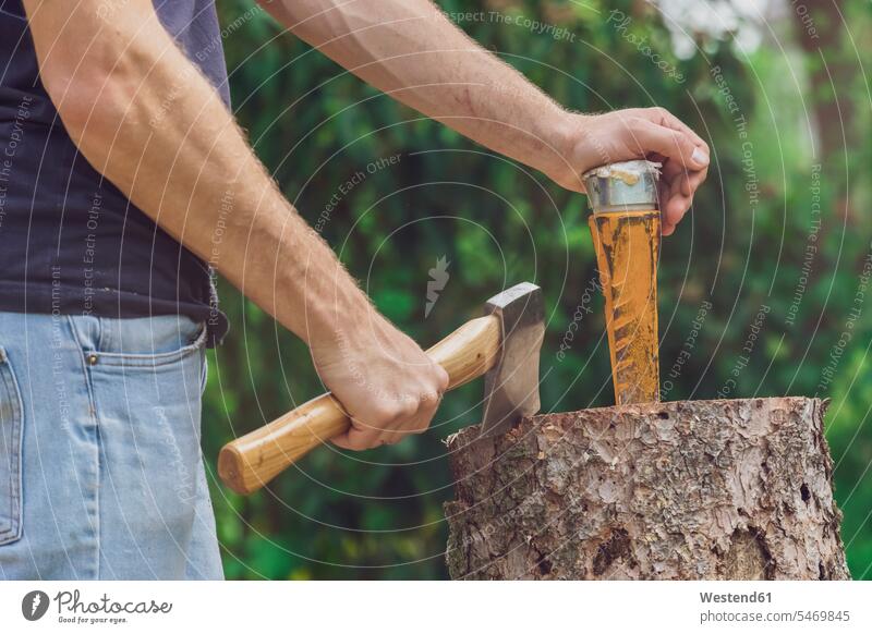 Man standing at a tree trunk holding an axe and a wedge human human being human beings humans person persons caucasian appearance caucasian ethnicity european 1