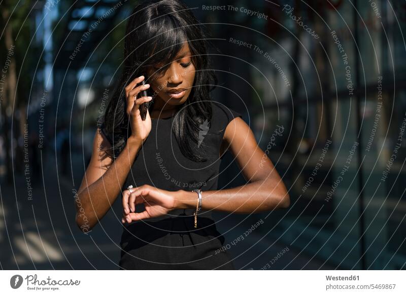 Businesswoman using smartphone and checking the time in the city human human being human beings humans person persons African black black ethnicity coloured