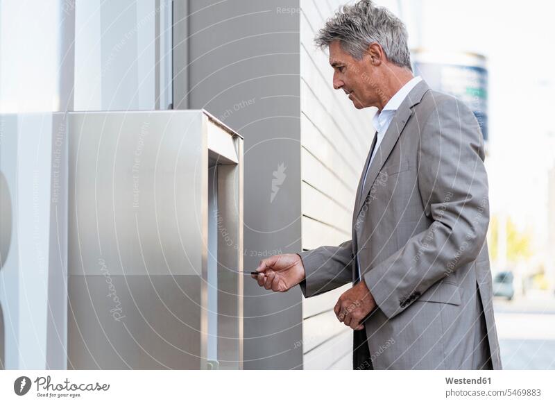 Mature businessman withdrawing money at an ATM business life business world business person businesspeople Business man Business men Businessmen finances