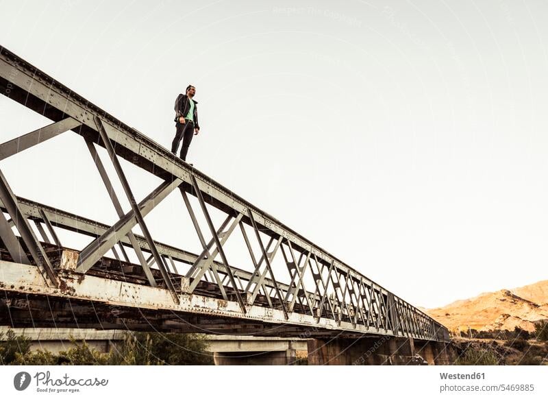 Man standing on metal bar of an old railway bridge free Liberty free time leisure time Distinct individual Lifestyle bravery risky on the go on the road