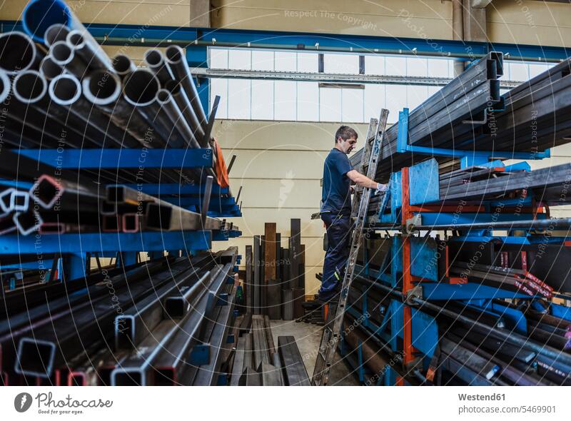 Man working with metal bars on a shelf in a factory human human being human beings humans person persons caucasian appearance caucasian ethnicity european 1