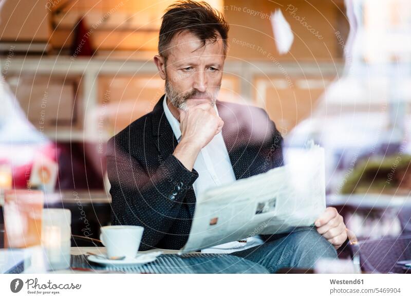 Portrait of pensive mature businessman reading newspaper in a coffee shop newspapers thoughtful Reflective contemplative Businessman Business man Businessmen