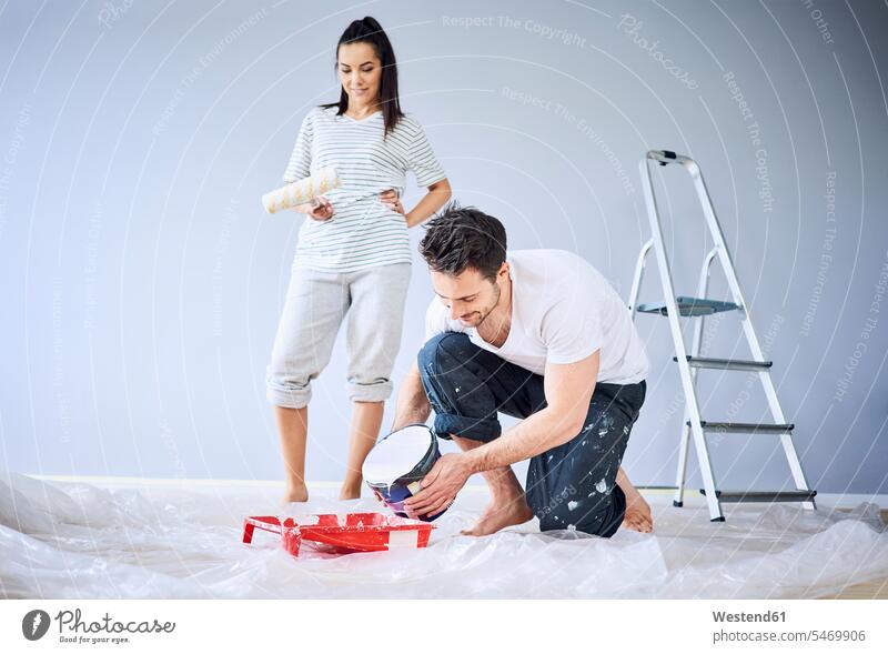 Happy couple painting in apartment together flat flats apartments happiness happy twosomes partnership couples new people persons human being humans