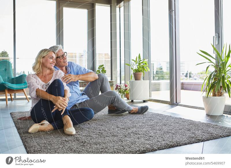 Smiling mature couple relaxing at home looking out of window view seeing viewing smiling smile windows twosomes partnership couples relaxed relaxation people