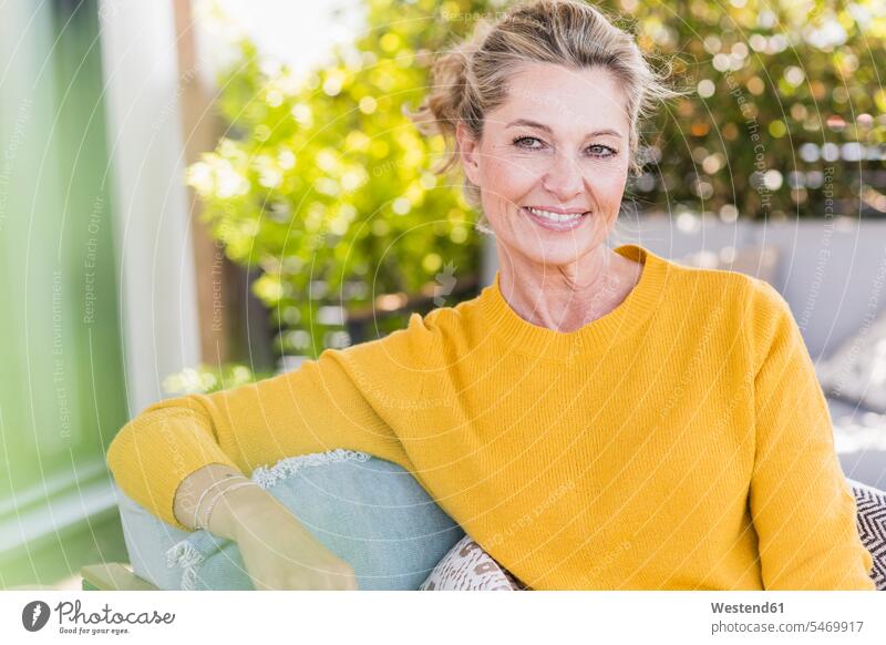Portrait of smiling mature woman sitting on terrace jumper sweater Sweaters chairs Arm Chair Arm Chairs armchairs relax relaxing smile Seated relaxation delight