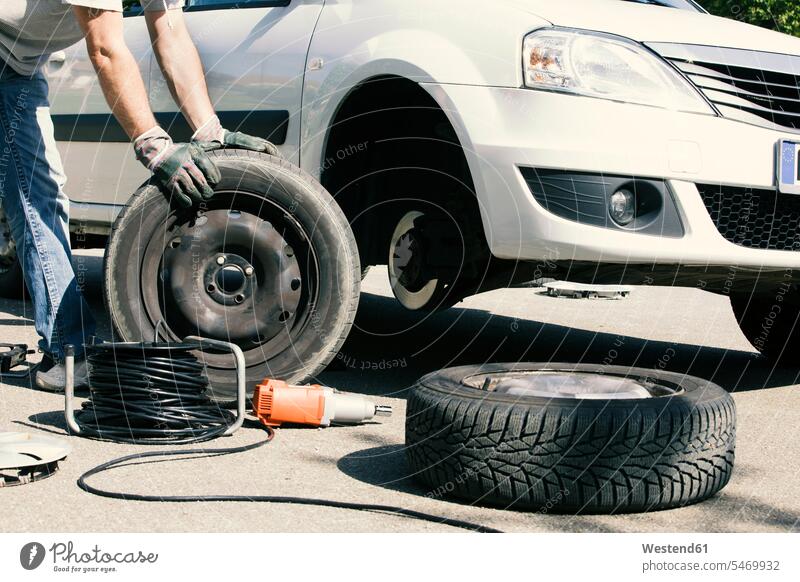 Man changing car tires, partial view tyre man men males change tire change wheel change tyre change car tyre car tyres Adults grown-ups grownups adult people