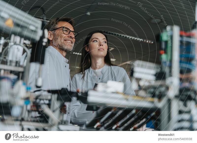 Thoughtful engineers looking away while standing by machinery in laboratory color image colour image indoors indoor shot indoor shots interior interior view