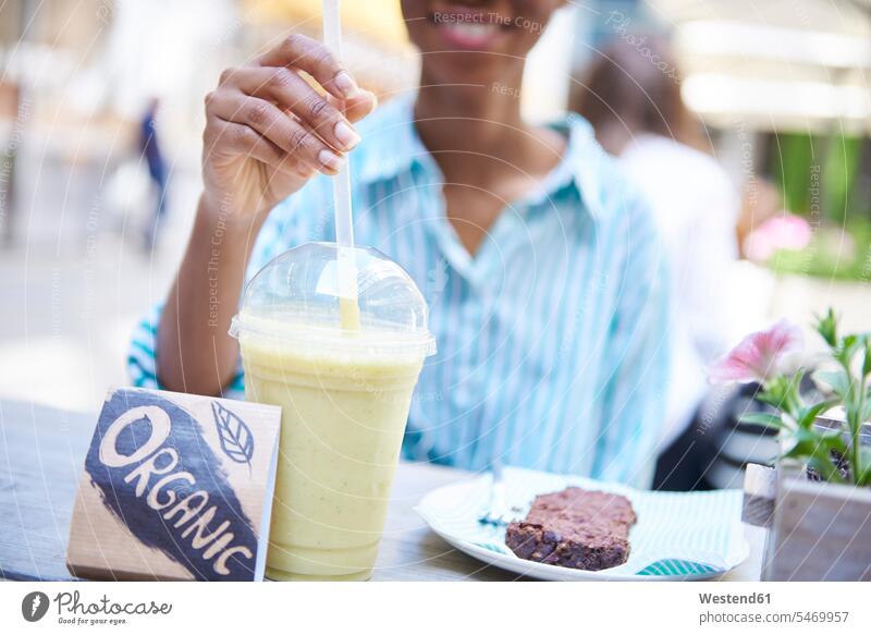Woman drinking organic smoothie at pavement cafe, partial view outdoor cafes woman females women Smoothies product products Adults grown-ups grownups adult