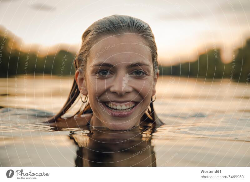 Young woman swimming in lake at sunset relax relaxing in the evening summer time summertime summery delight enjoyment Pleasant pleasure happy wetness