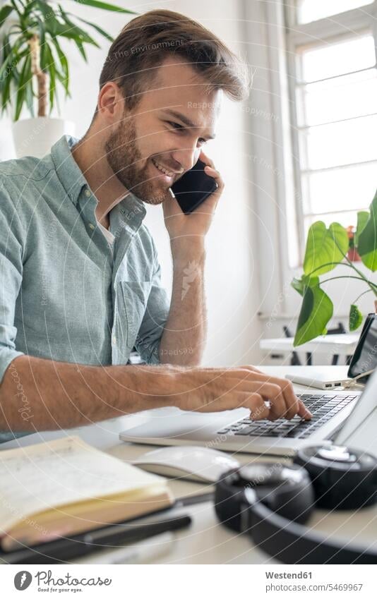 Smiling man on the phone at desk in office Occupation Work job jobs profession professional occupation business life business world business person