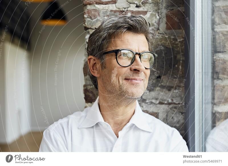 Portrait of smiling businessman wearing glasses looking out of window windows specs Eye Glasses spectacles Eyeglasses portrait portraits Businessman
