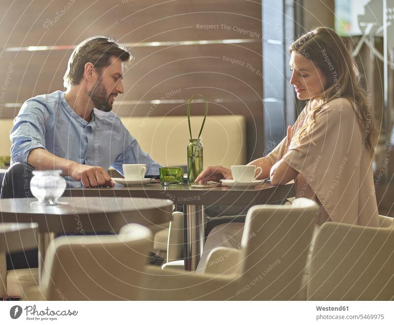 Man and woman sitting at table drinking coffee Coffee Table Tables colleagues Seated Drink beverages Drinks Beverage food and drink Nutrition Alimentation