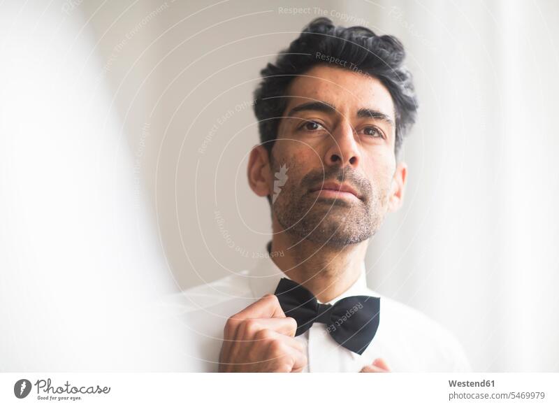 Portrait of man adjusting his bow tie portrait portraits bow-tie Bow Ties bowtie men males bows Adults grown-ups grownups adult people persons human being