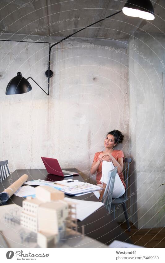 Portrait of smiling businesswoman sitting at table in a loft with documents and laptop lofts Laptop Computers laptops notebook businesswomen business woman